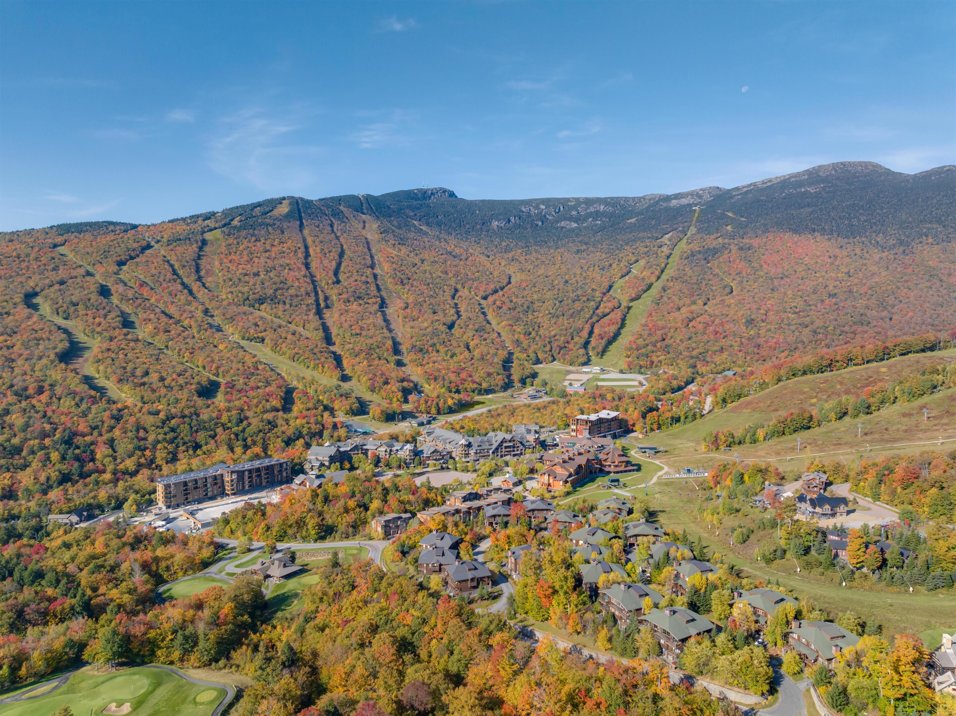 Un complexe hôtelier comprenant plusieurs bâtiments, un terrain de golf et un paysage montagneux en toile de fond.
