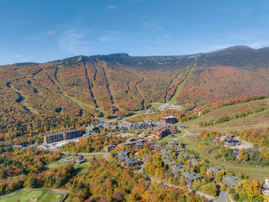 Un complexe hôtelier comprenant plusieurs bâtiments, un terrain de golf et un paysage montagneux en toile de fond.
