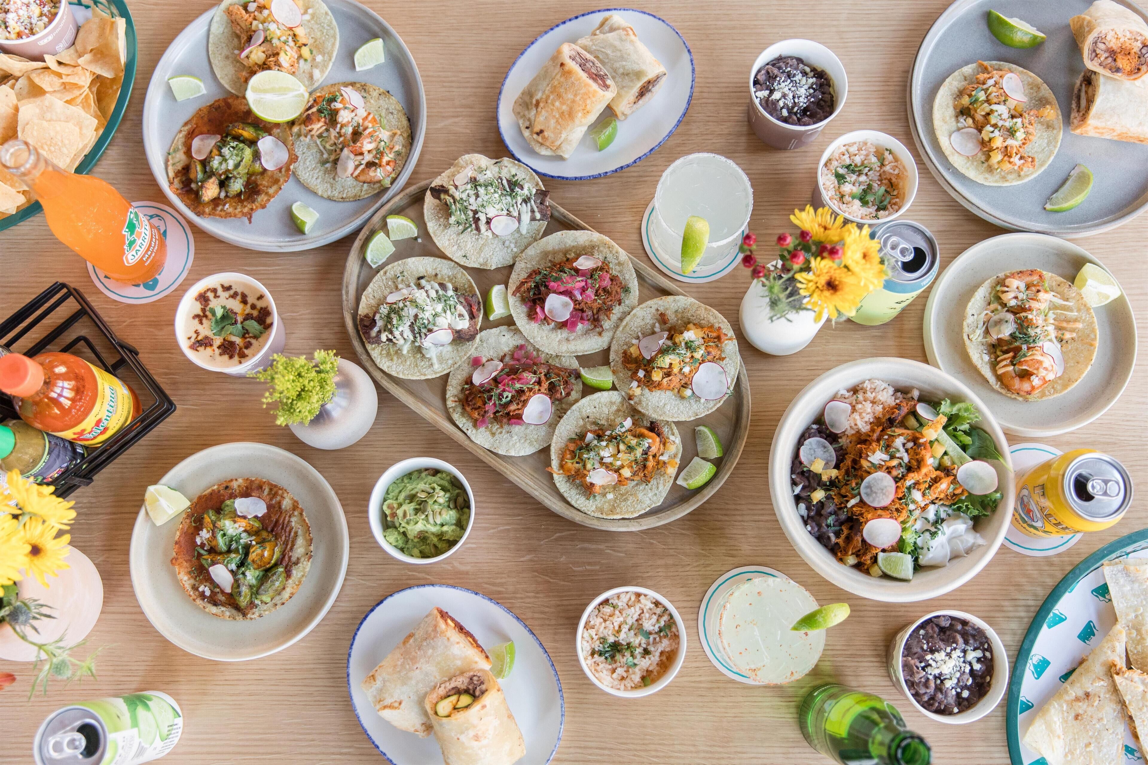 A table with various Mexican dishes, drinks, and condiments.