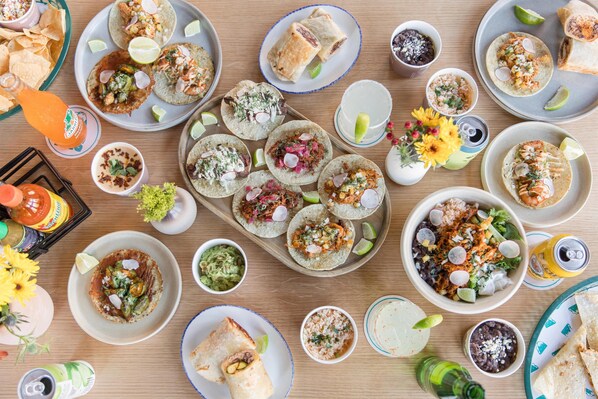 Una mesa con diversos platillos, bebidas y salsas mexicanas.