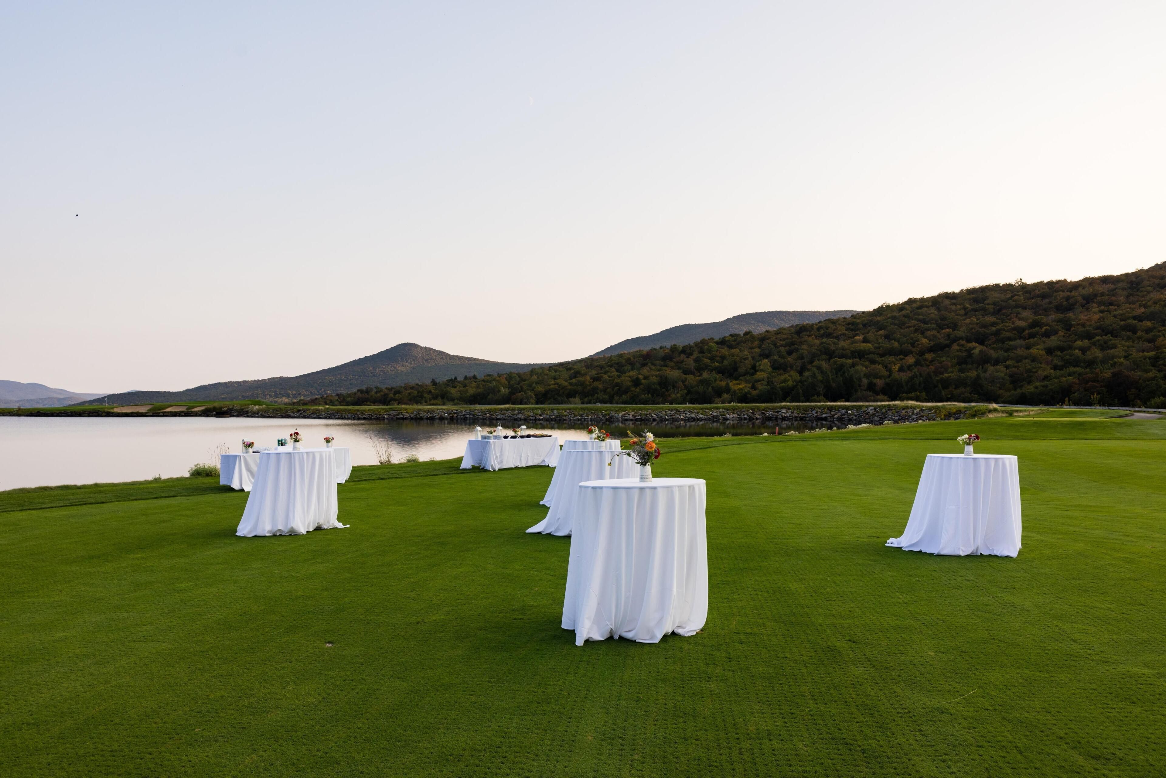 A golf course with white tables and chairs set up for an event.