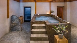 A spa area with a hot tub, stone steps, and a wooden bench with a vase of flowers. - The Lodge at Spruce Peak, a Destination by Hyatt Residence (Stowe)
