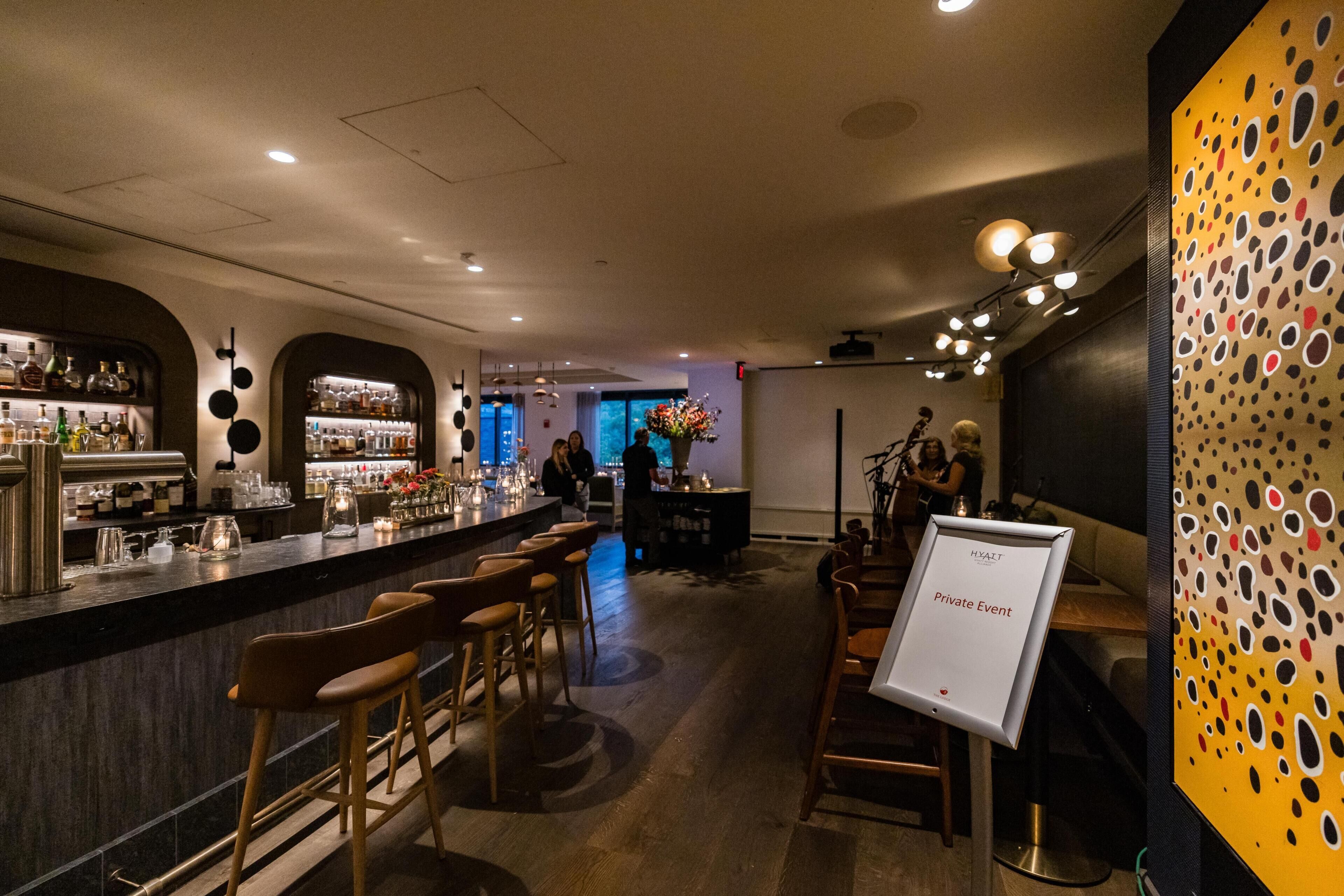 Un espace bar avec des tabourets, un comptoir et un panneau indiquant qu’un événement privé y est organisé.