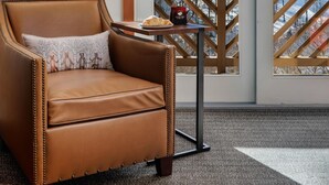 A room with a leather chair, a lamp, and a view of a snowy mountain landscape through large windows. - The Lodge at Spruce Peak, a Destination by Hyatt Residence (Stowe)