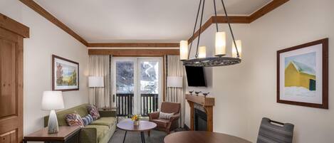 A furnished living room with a sofa, armchair, round table, and a fireplace.