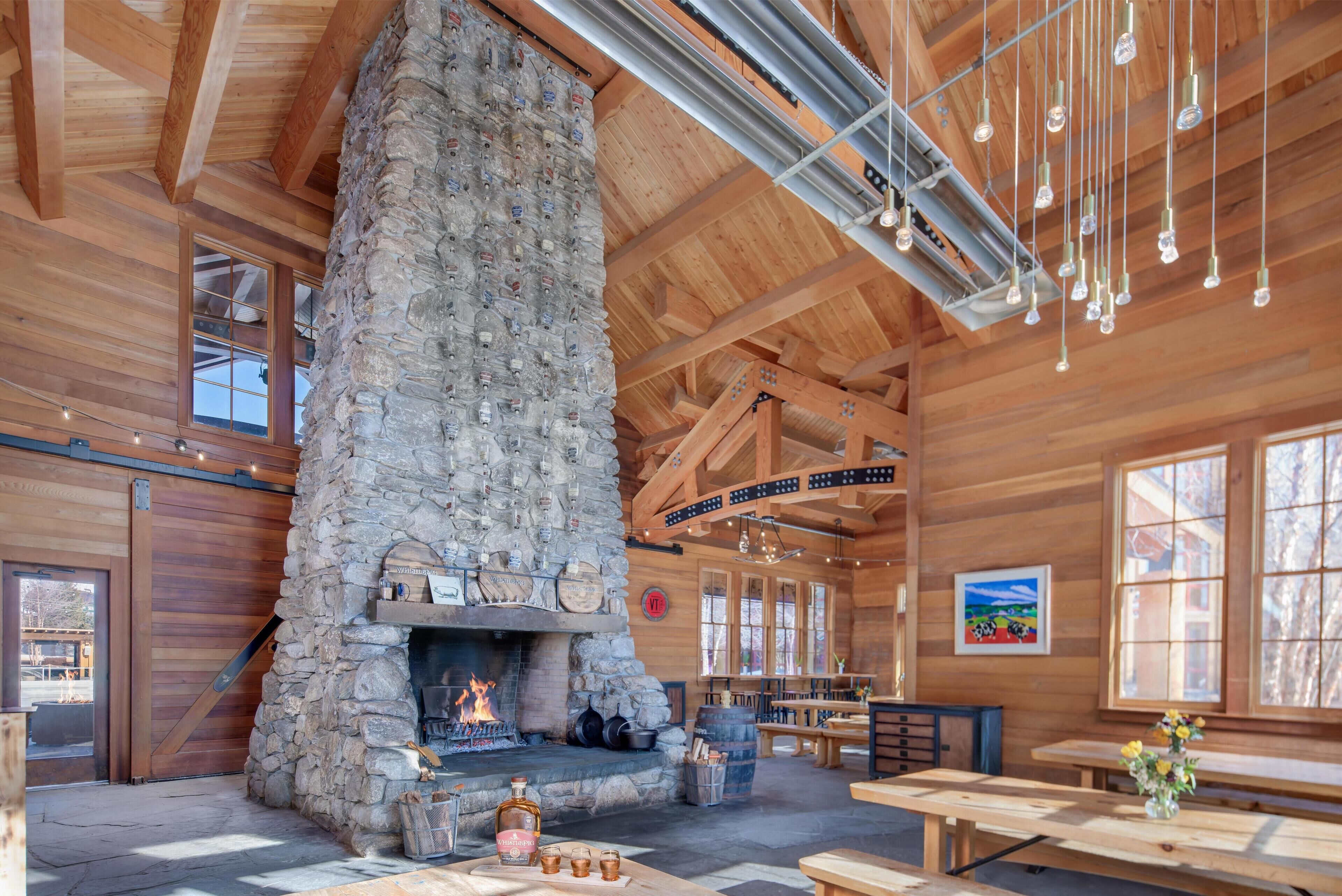 Un interior rústico con chimenea de piedra, vigas de madera y lámparas colgantes.