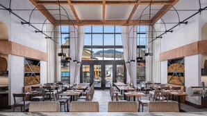 A spacious restaurant with high ceilings, large windows, and a view of mountains. - The Lodge at Spruce Peak, a Destination by Hyatt Residence (Stowe)