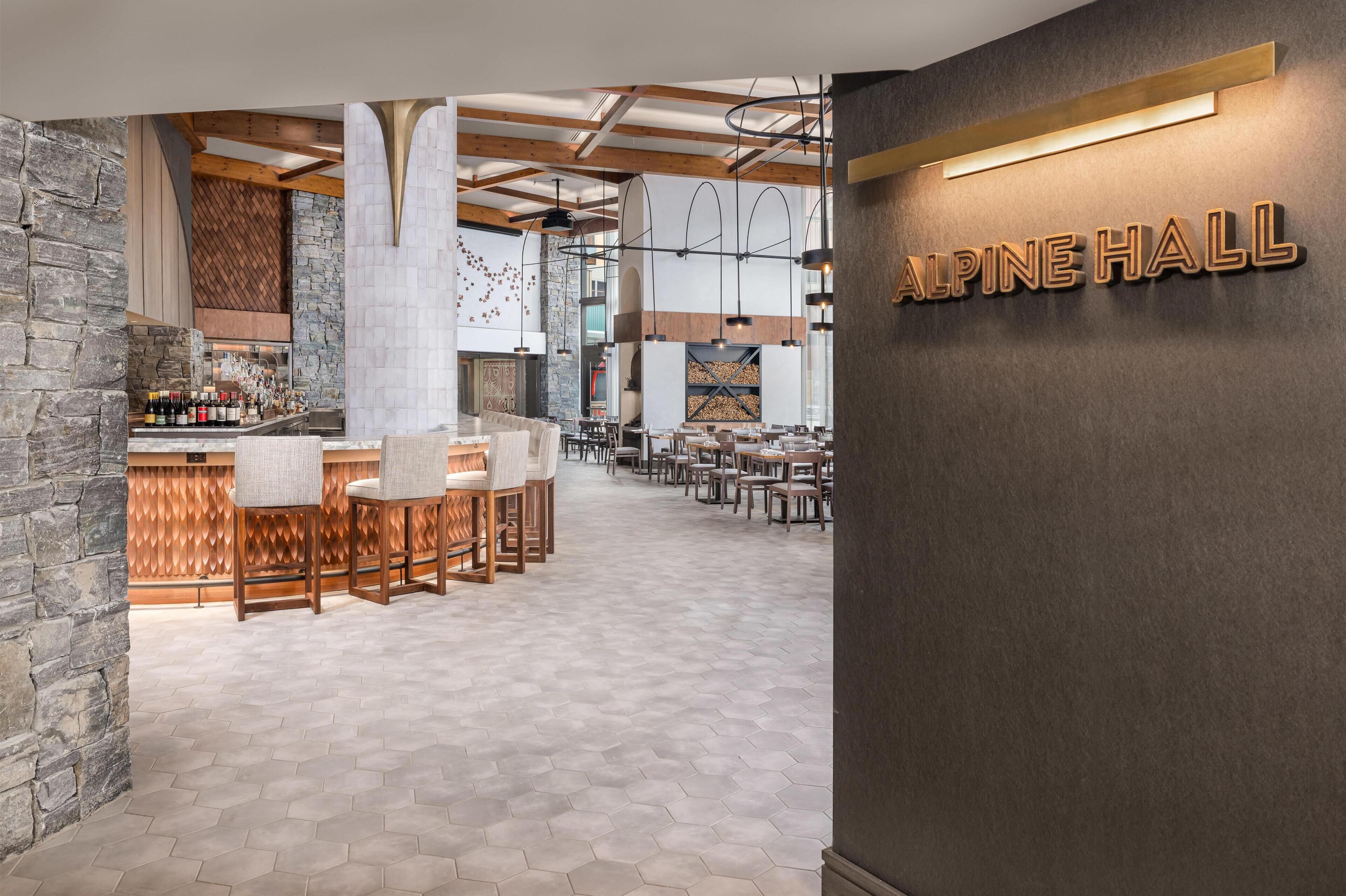 Un intérieur moderne comprenant un bar, des espaces pour s’asseoir et une cheminée.