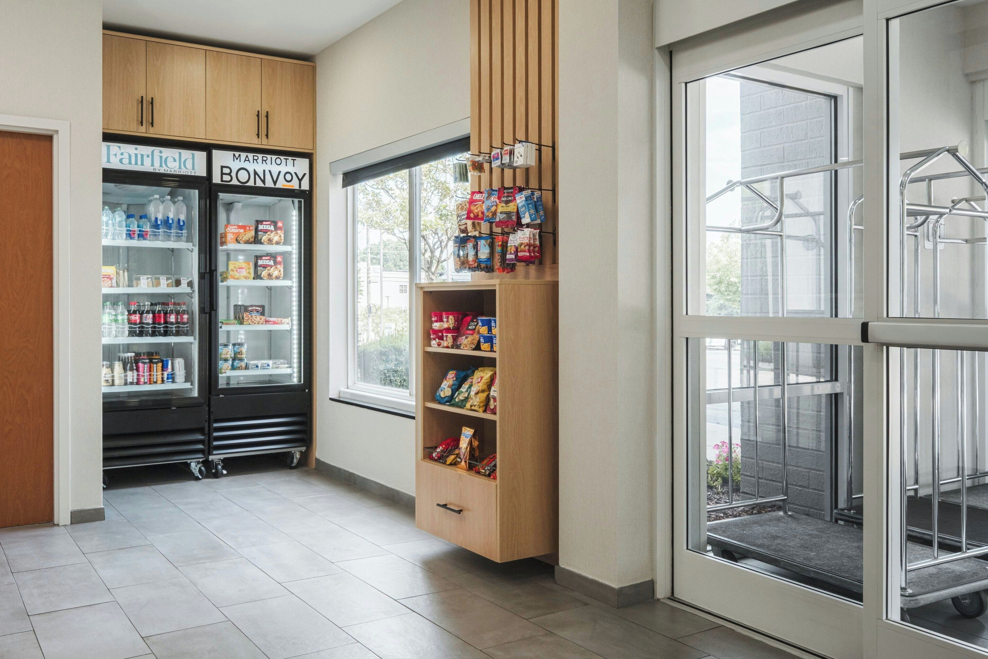 A hotel room with a minibar, a refrigerator stocked with beverages and snacks, and a window with a view of the outside.