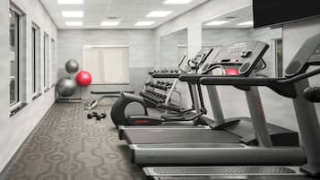 A gym with treadmills, dumbbells, and exercise balls.