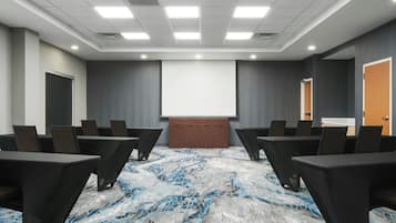Une salle de conférence équipée d’un écran de projection, d’un tableau blanc et d’un sol recouvert de moquette.