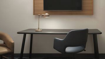 Et moderne værelse med skrivebord, stol, lampe og et fjernsyn ophængt på væggen.