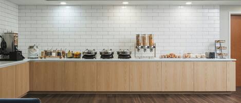 Una cocina moderna con azulejos blancos tipo metro, armarios de madera y una barra desayunadora.