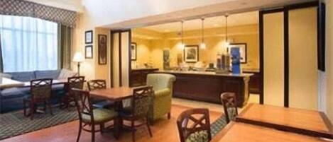 Une chambre d’hôtel comprenant un coin repas, un canapé et un coin cuisine.