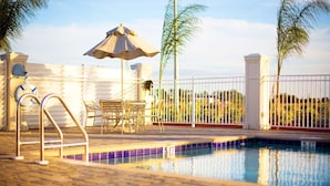A swimming pool with a white fence, lounge chairs, and an umbrella. - Hampton Inn & Suites Lake Wales (Lake Wales)
