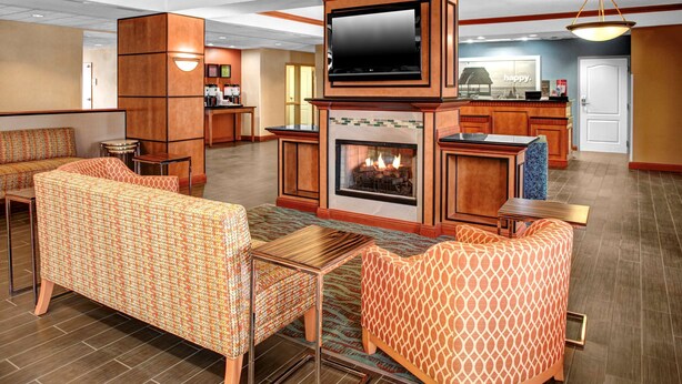 A hotel lobby with a fireplace, seating area, and a television. - Hampton Inn Coldwater (Coldwater)