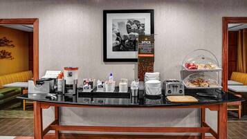 A buffet setup with various food items, a coffee machine, and a toaster.