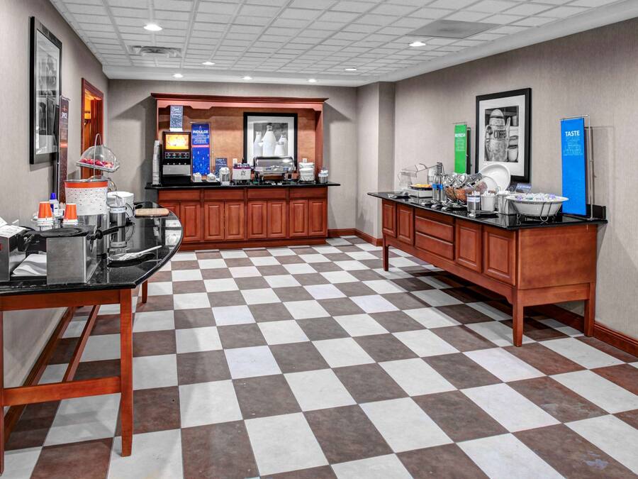 Un vestíbulo de hotel con piso a cuadros, una estación de café y un mostrador de recepción.