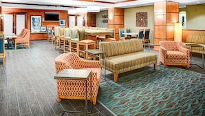 A hotel lobby with a dining area, seating arrangements, and a television on the wall. - Hampton Inn Coldwater (Coldwater)