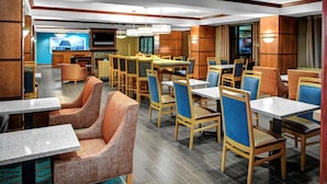 A hotel dining area with multiple tables and chairs, a television, and a bar area. - Hampton Inn Coldwater (Coldwater)