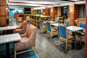 Un comedor de hotel con varias mesas y sillas, una televisión y una zona de bar.