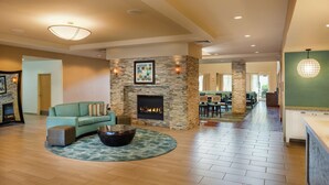 A spacious living room with a stone fireplace, a green sofa, and a coffee table. - Homewood Suites by Hilton Virginia Beach/Norfolk Airport (Virginia Beach)