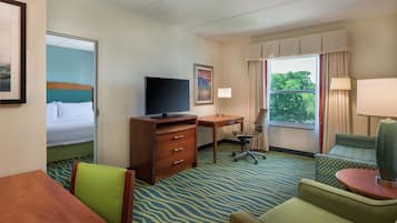 Habitación de hotel con cama, escritorio, silla, mesa y vistas al exterior.