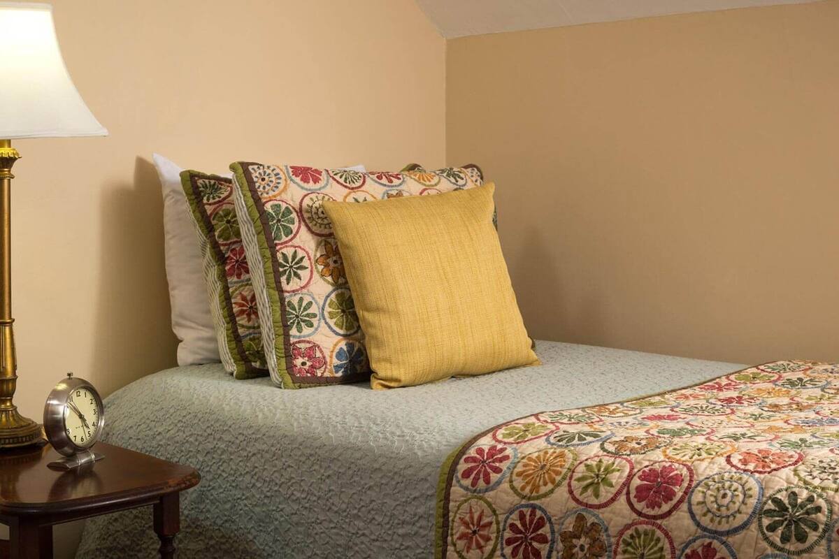 A bedroom with a bed, a nightstand, a lamp, and a clock.
