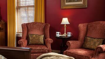 A room with two armchairs, a bedside table with a lamp, and a framed picture on the wall.