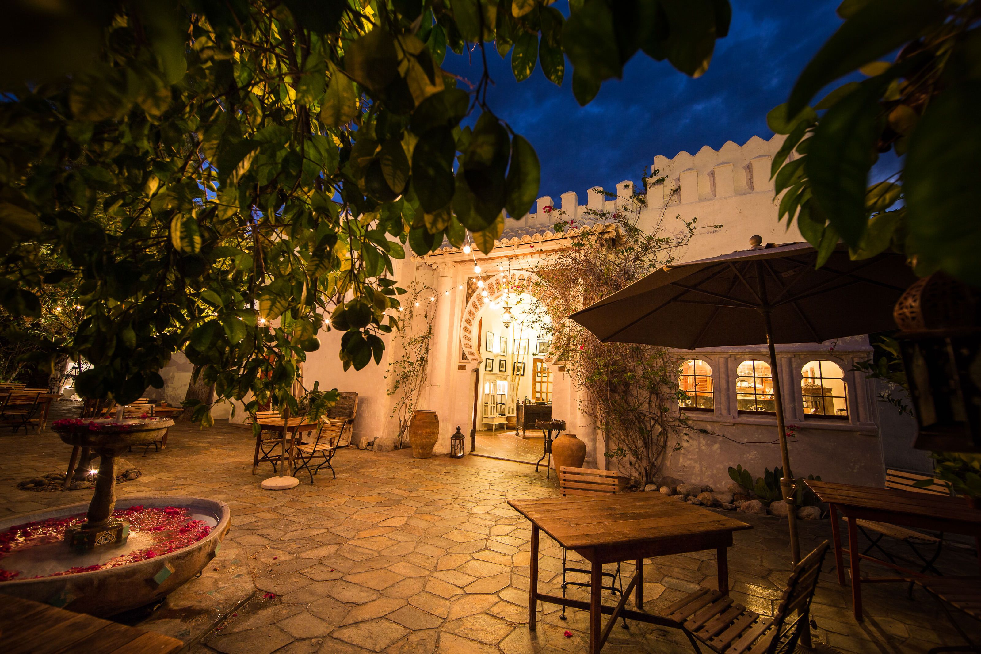 An outdoor patio area with stone flooring, wooden furniture, and a fountain.