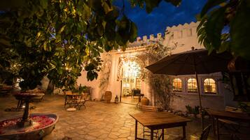 An outdoor patio area with stone flooring, wooden furniture, and a fountain.