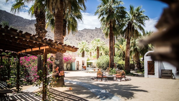 A courtyard with palm trees, a pergola, and outdoor seating. - Korakia Pensione (Palm Springs)