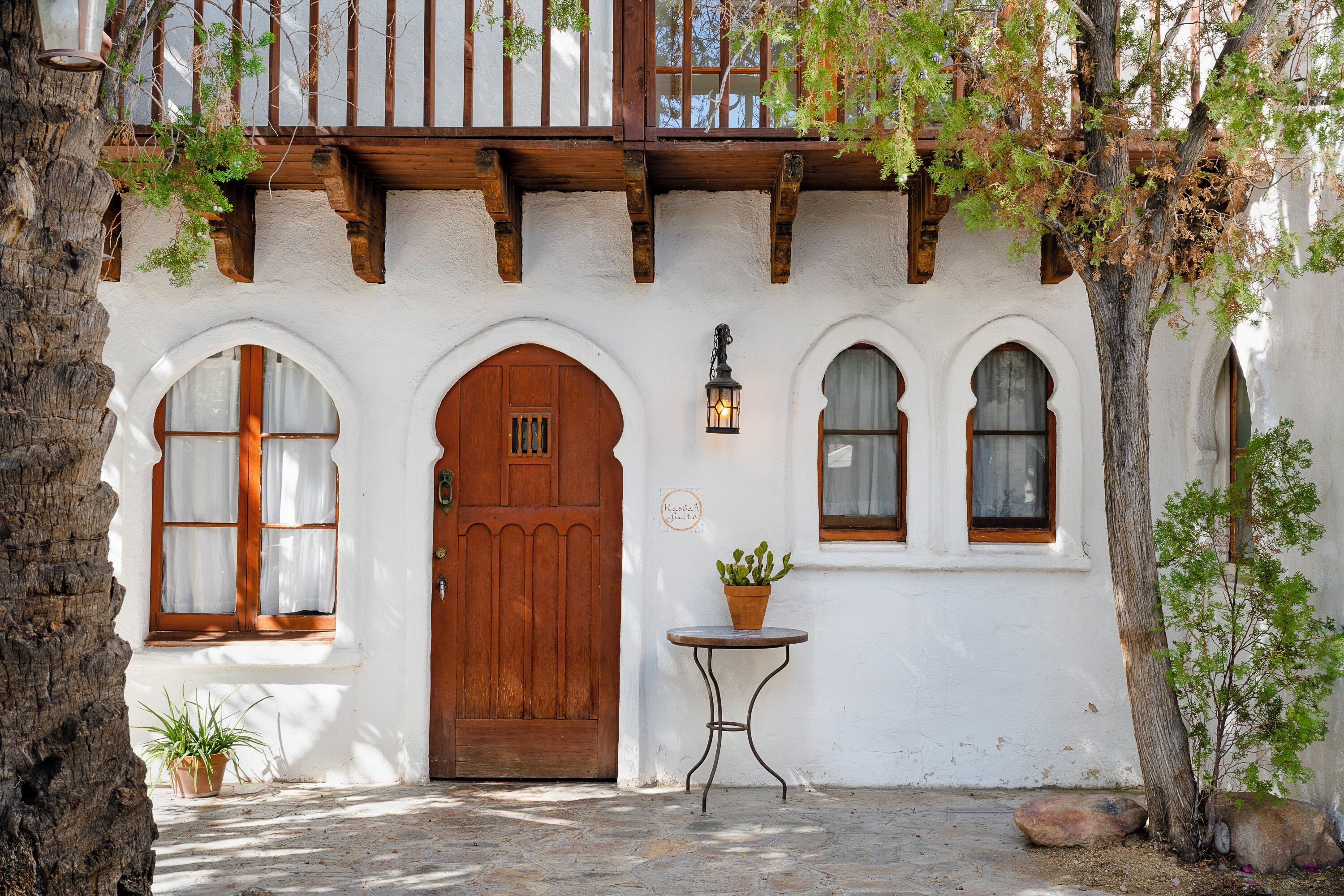 A traditional building with a wooden door, arched windows, and a small table with a potted plant.