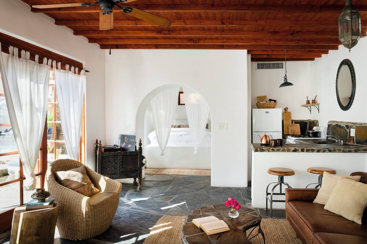 A cozy living area with a wicker chair, a leather sofa, and a stone floor.