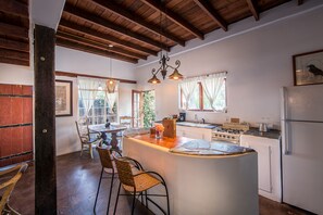 A kitchen with a central island, wooden ceiling beams, and a refrigerator.