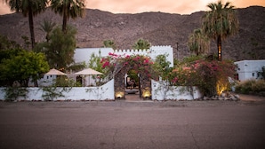 A white building with a stone archway, palm trees, and a mountain in the background. - Korakia Pensione (Palm Springs)
