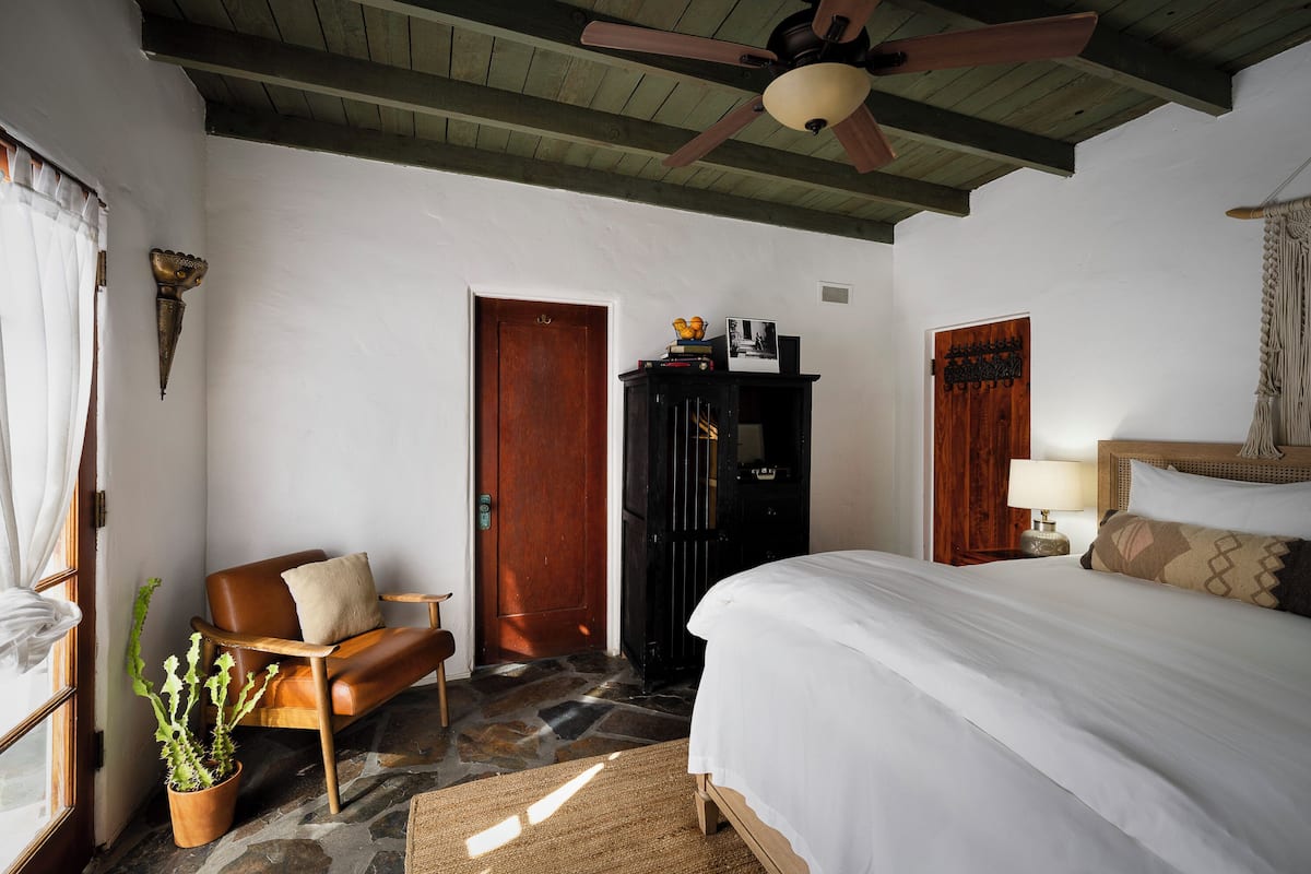 A bedroom with a bed, a chair, a wardrobe, and a ceiling fan.