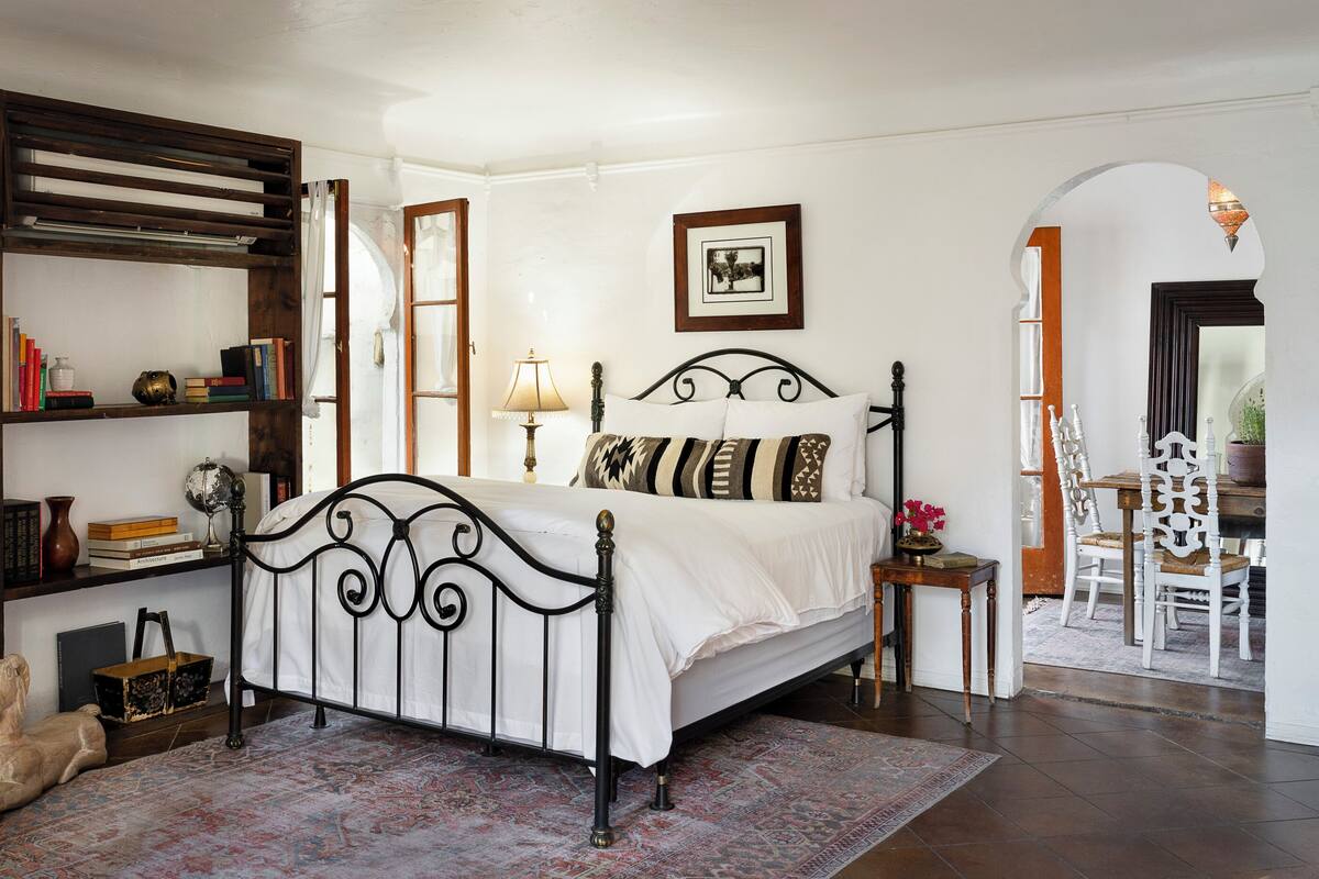 A bedroom with a bed, a bookshelf, a desk, and a chair.