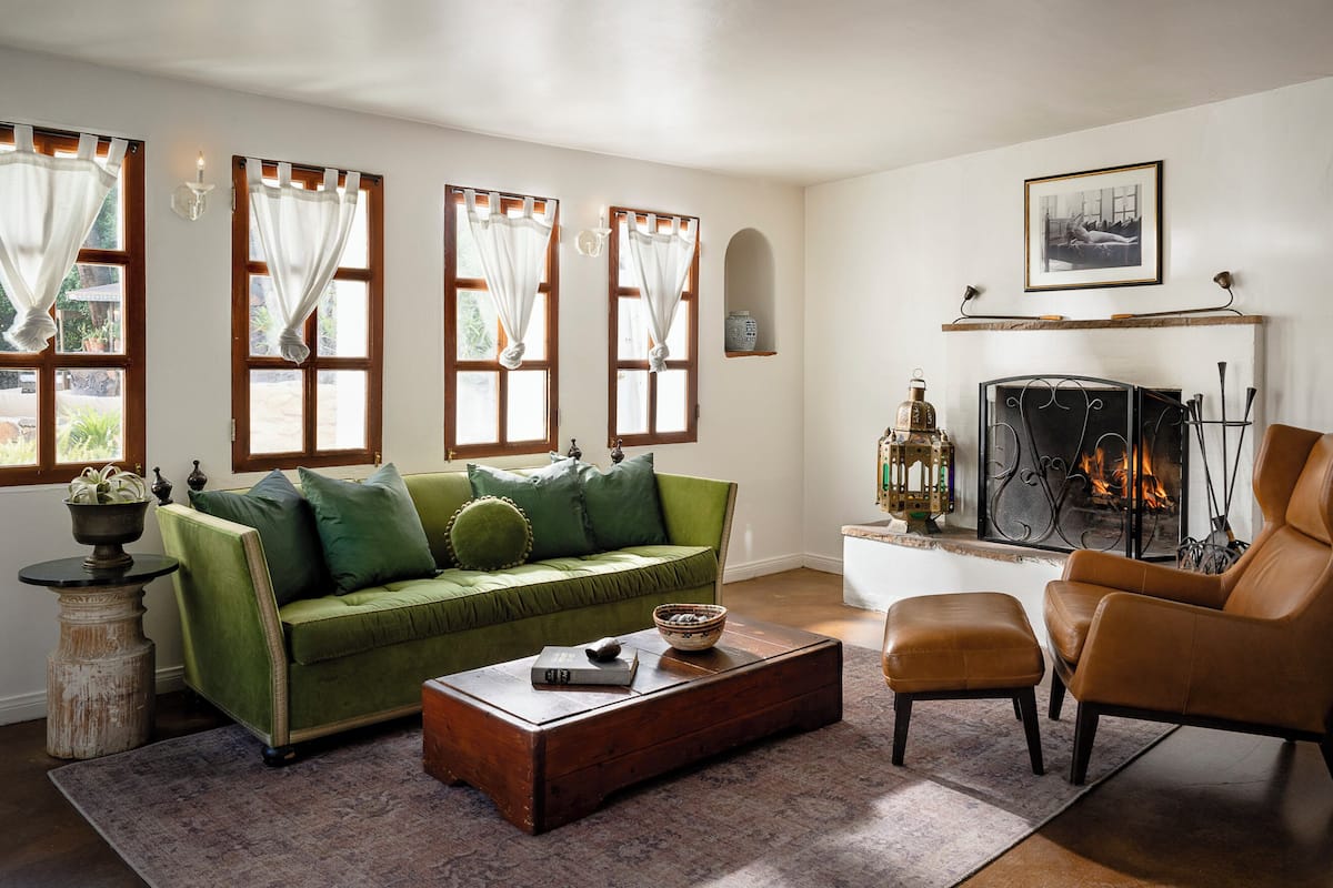 A living room with a green sofa, a brown leather armchair, a wooden coffee table, and a fireplace.