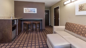 Una habitación de hotel compacta con kitchenette, un sofá y un suelo estampado.