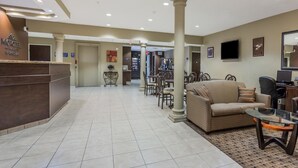 Un hall de hotel con una recepción, una zona de estar y un televisor.
