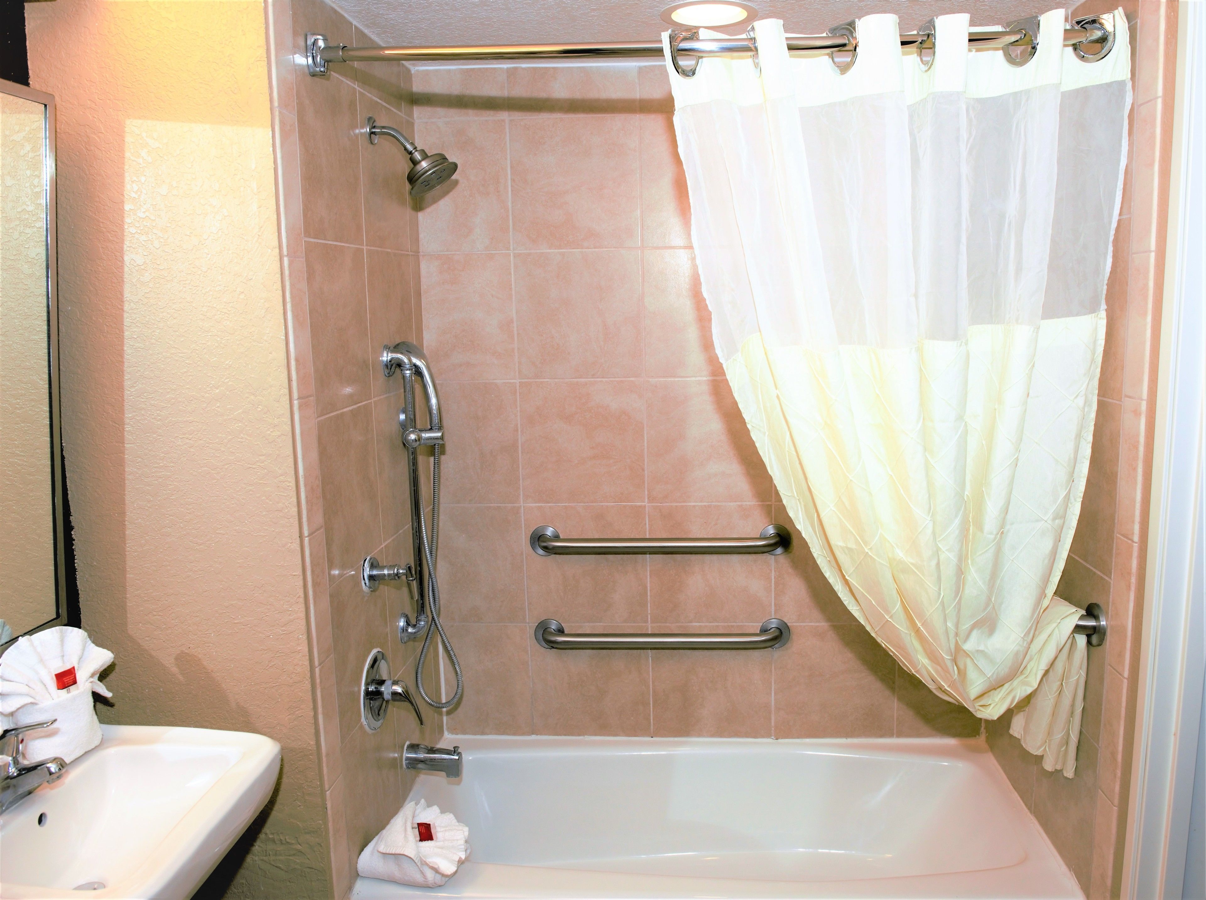 Un baño con bañera, ducha y barra de apoyo.