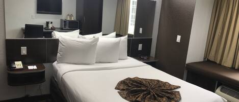 Hotelkamer met een groot bed, een bureau met telefoon, een magnetron en een flatscreen televisie aan de muur.