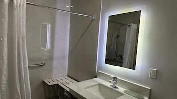 Une salle de bain moderne avec une douche à parois de verre, un lavabo blanc avec un miroir au-dessus et un porte-serviettes.