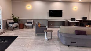 A modern living room with a flat-screen TV, two sofas, a coffee table, and a fireplace. - La Quinta Inn & Suites by Wyndham Alamo - McAllen East (Alamo)