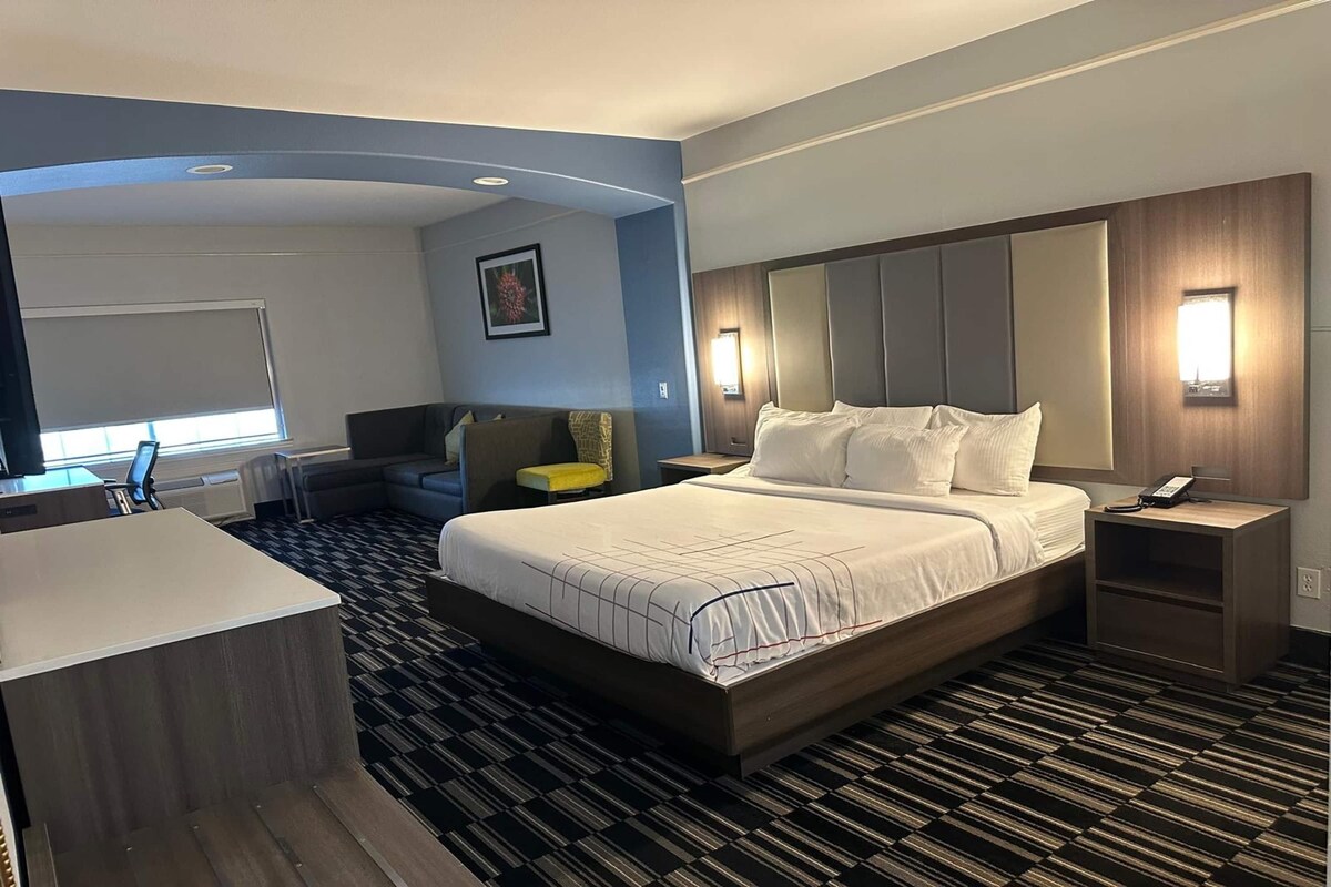 A modern hotel room with a large bed, a desk, and a chair.