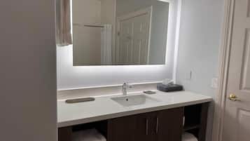 A bathroom with a white sink, a mirror, and a towel rack.