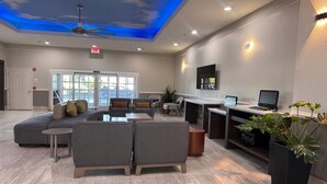 A modern lounge area with a ceiling design, seating arrangements, and a reception desk. - La Quinta Inn & Suites by Wyndham Alamo - McAllen East (Alamo)
