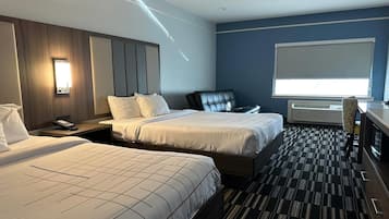 A hotel room with two beds, a desk, a chair, a TV, and a large window.