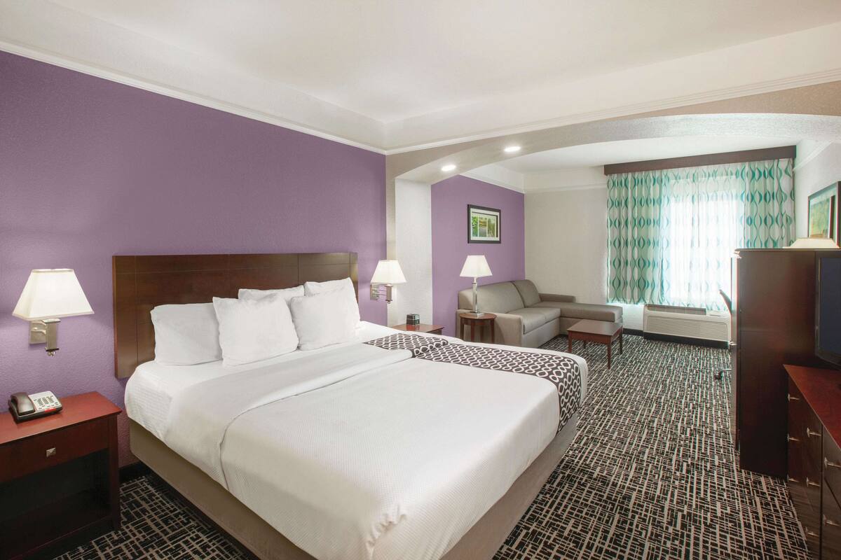 A hotel room with a large bed, two bedside tables, a desk, a chair, and a television.